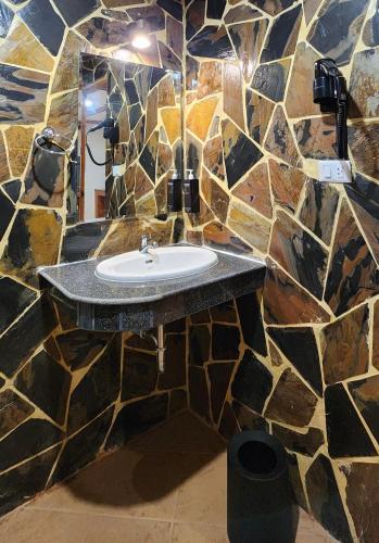 a bathroom with a sink in a stone wall at Arya Suites Patong Beach in Patong Beach