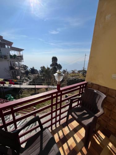 un par de sillas en un balcón con vistas en Kanatal stay, en Dhanaulti