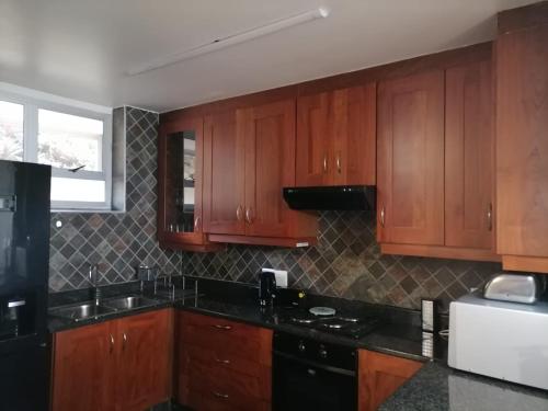 une cuisine avec des placards en bois et des comptoirs noirs dans l'établissement Inyoni Rocks Cabanas 15, à Amanzimtoti