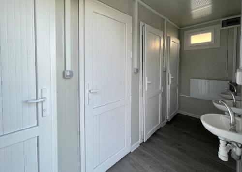 ein Badezimmer mit zwei Waschbecken und einer weißen Tür in der Unterkunft Eco Farm Camping 'de Waeldernis' in De Waal