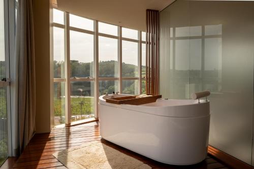 a bathroom with a tub and a large window at Casa Valduga Pousada Boutique in Bento Gonçalves