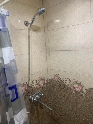 a shower with a glass door with flowers on the wall at Джермук 3-комнатная квартира in Jermuk