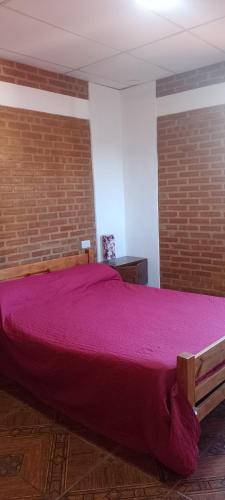 a large bed in a room with a brick wall at Bella Fefi in Villa Cura Brochero