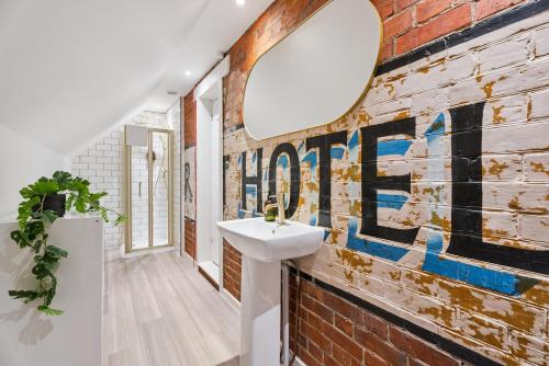 亨利昂泰晤士Flower Pot Hotel的浴室里有洗手池和一面带镜子的砖墙。