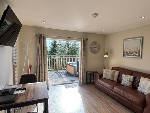 a living room with a couch and a balcony at Beechnut Lodge with Hot Tub in Cupar
