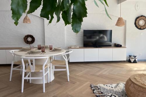 ein Wohnzimmer mit einem weißen Tisch und einem Fernseher in der Unterkunft LoftAnno1940 in Lokeren