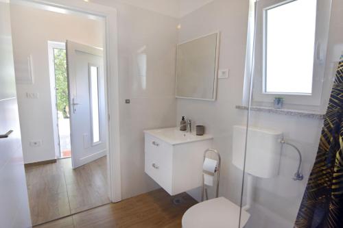 a white bathroom with a toilet and a sink at Modern holiday home with shared pool in Čepljani