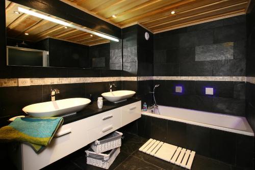 a black bathroom with two sinks and a bath tub at Odalys Chalet Leslie Alpen in Les Deux Alpes