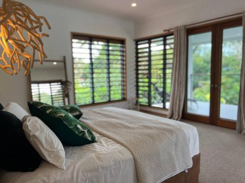 a large bedroom with a large bed with windows at BIG Beach House Tranquility in Kewarra Beach