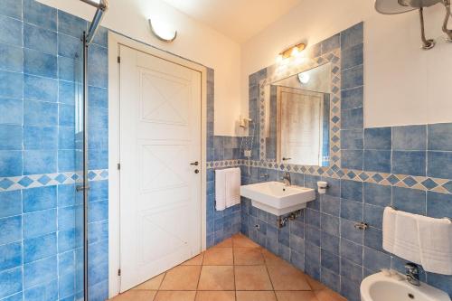 een blauw betegelde badkamer met een wastafel en een spiegel bij Cozy accommodation with shared pool in Vignola Mare