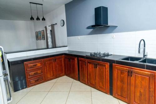een keuken met houten kasten en een spoelbak bij Maison avec Jardin à la Pyrot in Diego Suarez