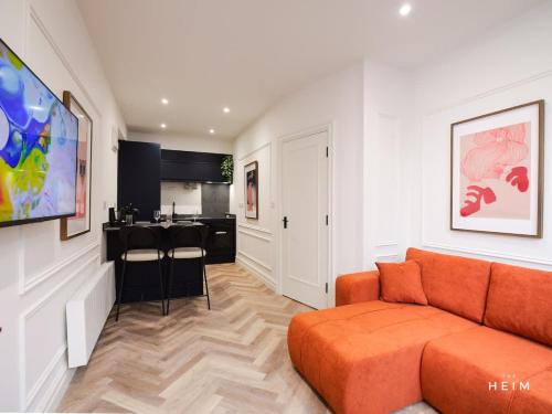 a living room with an orange couch and a kitchen at Calico at The Heim Residences in Manchester