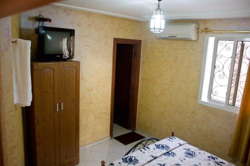 Schlafzimmer mit einem TV, einem Bett und einem Fenster in der Unterkunft Hotel Bab Boujloud in Fès