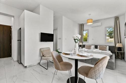a white living room with a table and chairs at STYLE°LIMASSOL in Limassol