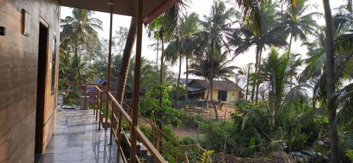戈卡尔纳Prakruti Home stay In Beach Side AC Room的通往棕榈树房屋的木制走道