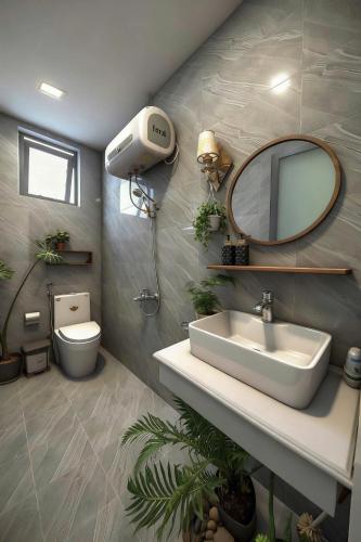 a bathroom with a sink and a mirror and a toilet at Le'Mon in Da Lat
