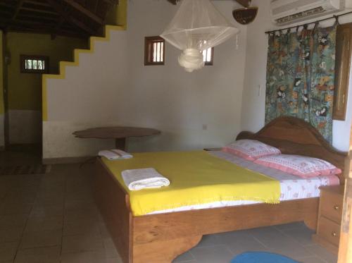 a bedroom with a bed with a yellow bedspread at Campement Le Cormoran in Ndangane