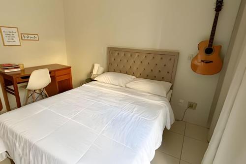een slaapkamer met een bed met een gitaar aan de muur bij No centro com Varanda, Smart Tv, Elevador e Garagem Paga in Viçosa