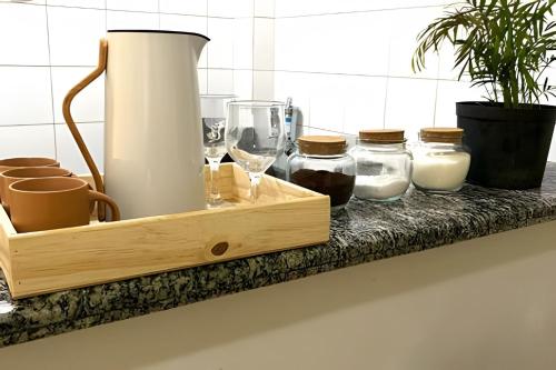 een houten dienblad met glazen en kannen melk op een aanrecht bij No centro com Varanda, Smart Tv, Elevador e Garagem Paga in Viçosa