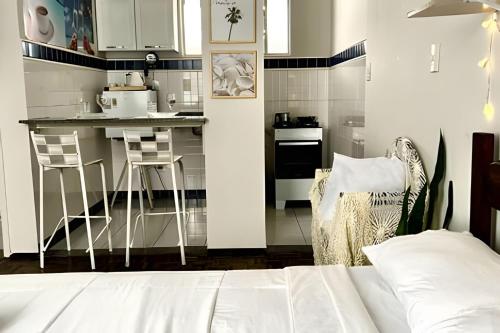 Zimmer mit einer Küche mit einer Theke und Stühlen in der Unterkunft Kitnet na rua da UFV com Smart TV e Garagem in Viçosa