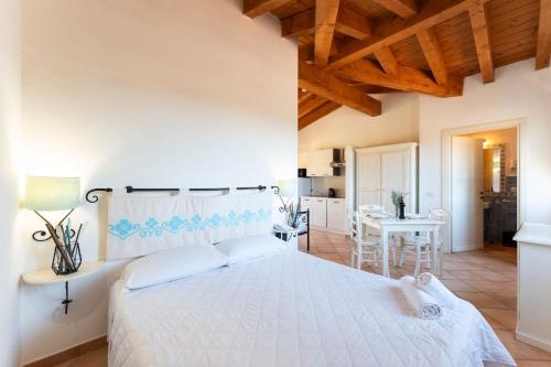 een slaapkamer met een groot wit bed en een tafel bij Functional studio with shared pool in Vignola Mare