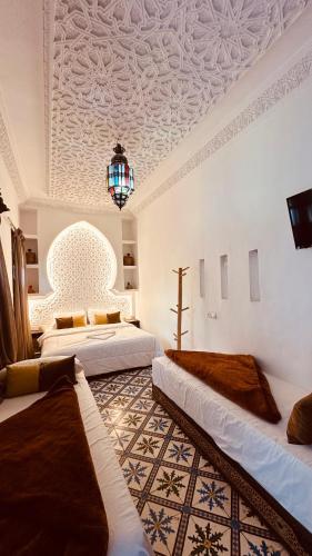 una stanza con tre letti e un soffitto con un lampadario di Riad 46 a Marrakech