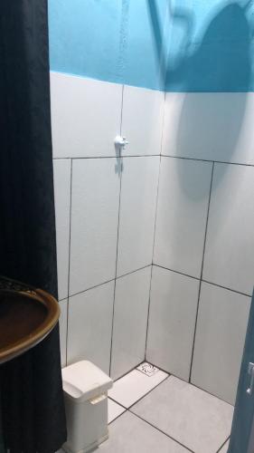 ein weiß gefliestes Badezimmer mit Toilette und Waschbecken in der Unterkunft Kit Net in Torres