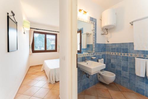 een blauw betegelde badkamer met een wastafel en een toilet bij Comfy studio with pool in Vignola Mare