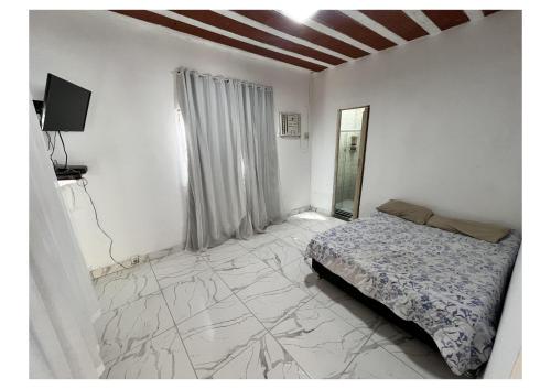 una camera da letto con un letto e uno specchio sul pavimento di Urban Executive Residence a Itaguaí