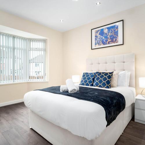 a bedroom with a large white bed with blue accents at Four Bed House - Sleeps 7 - Garden - Parking - Smart TV 6COK in Birmingham