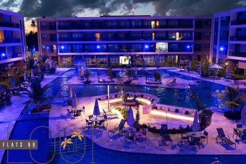 ein Hotelinnenhof mit Tischen und Stühlen vor einem Gebäude in der Unterkunft Malia Beach Porto Galinha By Loui in Ipojuca