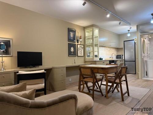 ein Wohnzimmer mit Tisch und Küche in der Unterkunft TatryTop Apartament Szałwiowy in Nowy Targ
