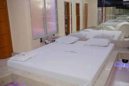 ein Badezimmer mit einem großen weißen Bett vor einem Spiegel in der Unterkunft Pousada Olimpo in Ananindeua