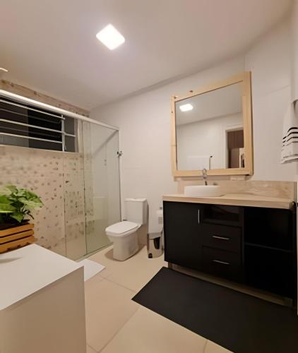 a bathroom with a sink and a mirror and a toilet at Apartamento Major Nicoletti in Gramado