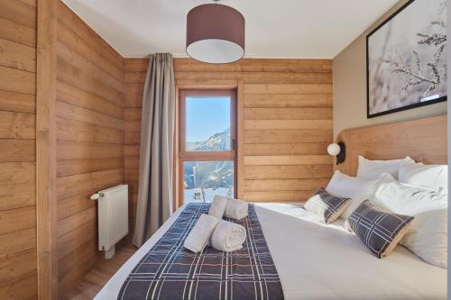 a bedroom with a large bed with a window at Résidence Odalys L'Ecrin Blanc in La Rosière