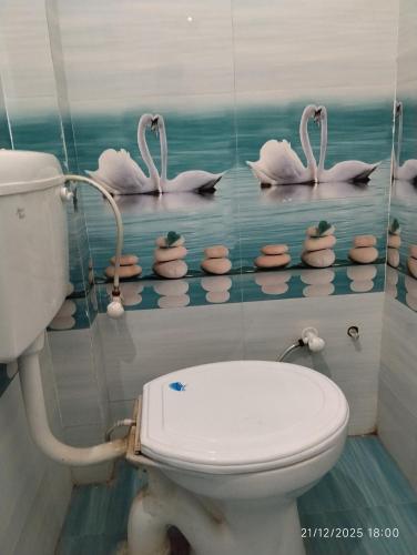 a bathroom with a toilet and some swans on the wall at Shree Balaji home stay Ayodhya contact number 92782-97365 in Ayodhya