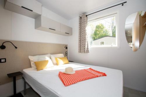 a bedroom with a white bed with a hat on it at Camping Les Pêcheurs - Maeva in Roquebrune-sur-Argens