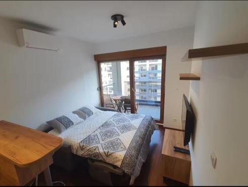 a bedroom with a bed and a table and a window at Master Quart studio apartment in Podgorica