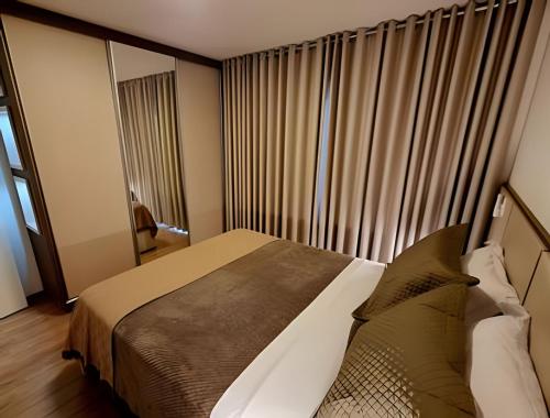 a bedroom with a bed and a window with curtains at Gramado Loft 105 in Gramado