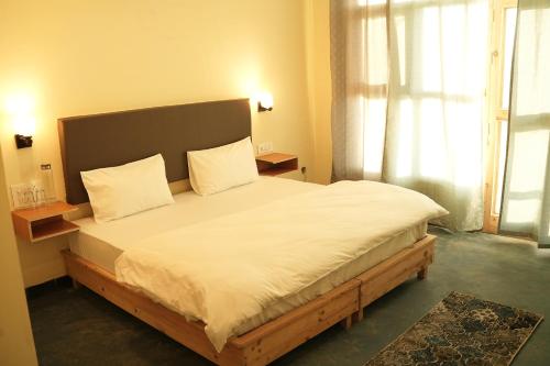 a bedroom with a large bed with white sheets at Hobo Hostel in Dharamshala