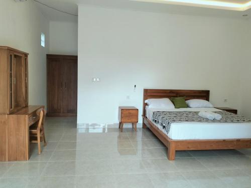 a bedroom with a bed and a dresser and a desk at Dharma Yoga Guest House Amed in Amed