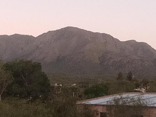 einen Berg in der Ferne mit einem Gebäude und Bäumen in der Unterkunft Los patos in Capilla del Monte