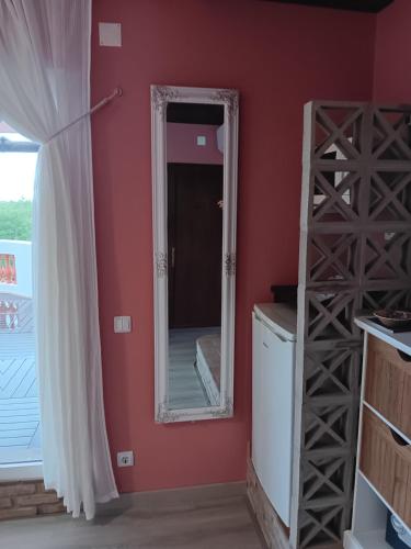 a mirror in a room with a red wall at Alojamento local Patudos, Suite com terraço privado in Tavira