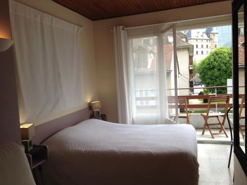 a bedroom with a bed and a large window at Hotel Sandra in Vizille