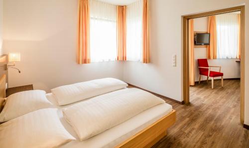a bedroom with a bed and a red chair at Gasthof Hotel Terzer in Cortaccia