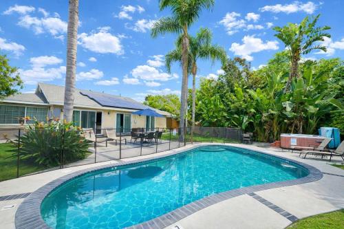 a swimming pool in front of a house with palm trees at Rainforest Villa 4 Bedroom PoolSpa Walk2Disneyland in Anaheim