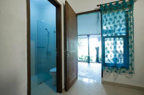 baño con ducha, aseo y puerta de cristal en Ronia Mountain Villa Lembang, en Lembang