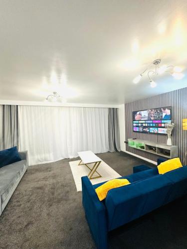 een woonkamer met een blauwe bank en een tv bij The Pheasant - Luxury 3-bedroom Apartment in Dartford in Dartford