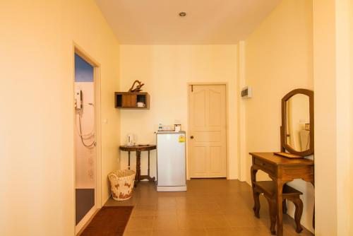 a kitchen with a refrigerator and a table and a mirror at Tum Baan Suan ตุ่มบ้านสวน in Chanthaburi