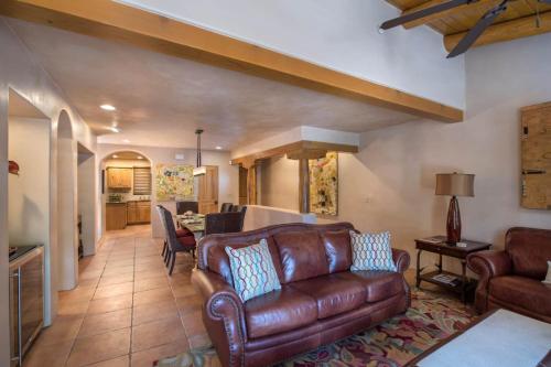 ein Wohnzimmer mit einer Ledercouch und einem Tisch in der Unterkunft Santa Fe Downtown Corner Courtyard @ El Corazon de Santa Fe in Santa Fe